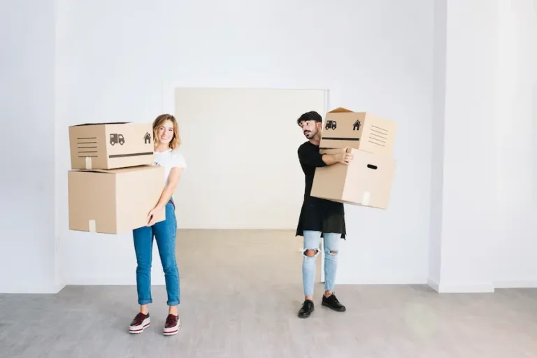 Ein Mann und eine Frau bringen nach dem Transport verpackte Möbel in die neue Wohnung.