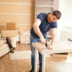 Ein Mann und eine Frau bauen Möbel für einen Umzug ab und verpacken sie