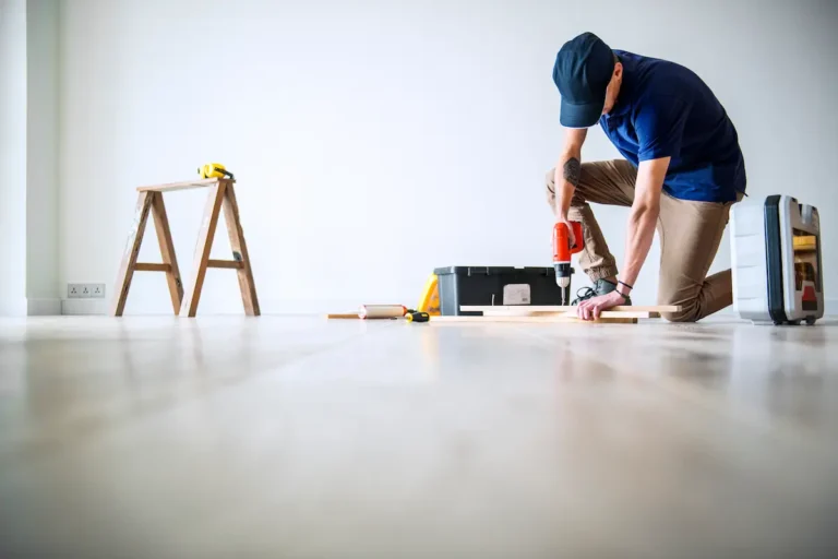 Im Vordergrund baut ein professioneller Möbelmonteur Möbel für einen Kunden zusammen.